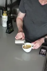 First frame of the next shot: milk pouring over the cup's rim
